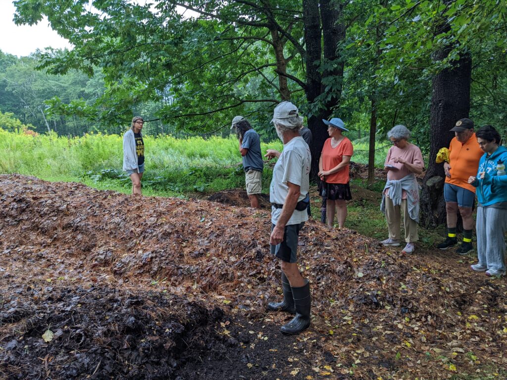 Tom Vigue shows his leaf mold piles to a group of tour attendees