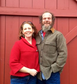 Grace Pond Farm Two people smiling in front of a red barn door